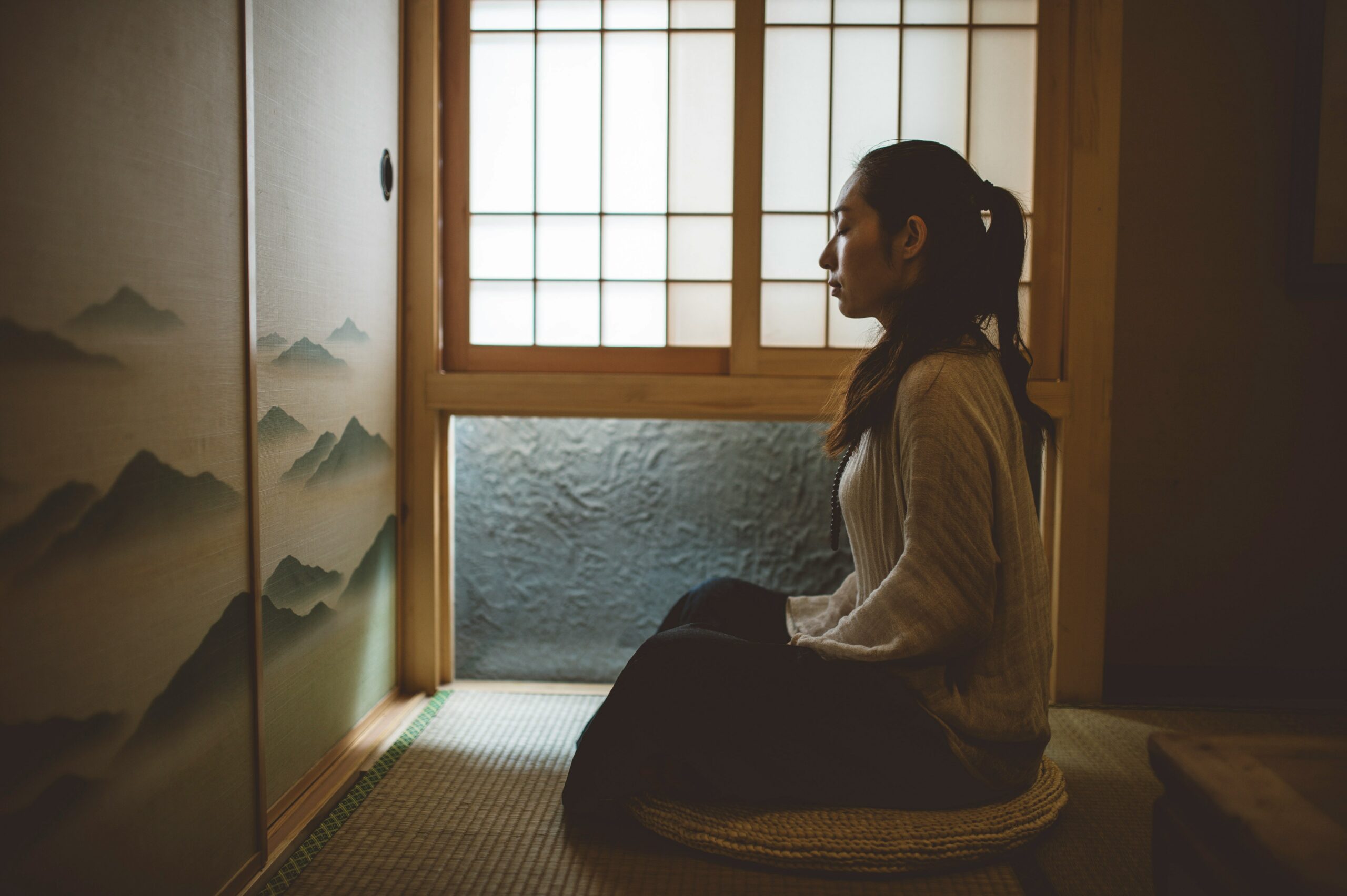 Žena koja sjedi u položaju za meditaciju na jastuku